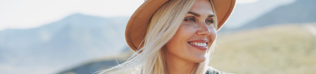 close up headshot of blonde woman in sunhat in the great outdoors smiling